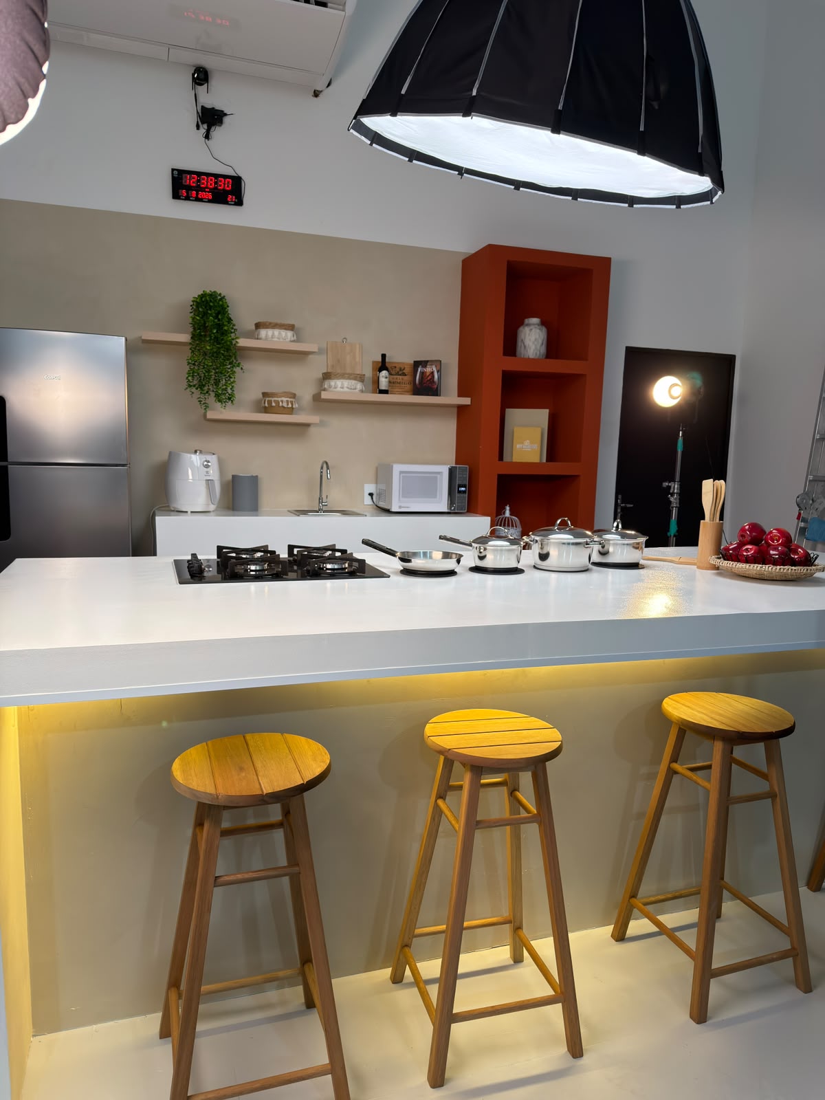 Bancada da cozinha do Estúdio 428 com cooktop, panelas e softbox de iluminação profissional