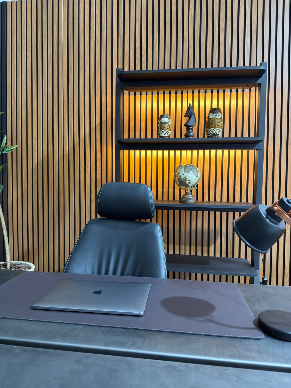 Cenário corporativo do Estúdio 428 com mesa, poltrona de couro e painel ripado iluminado
