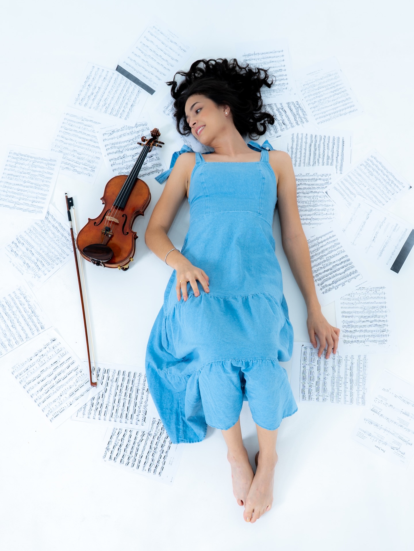 Violinista posando com partituras espalhadas em fundo branco no Estúdio 428
