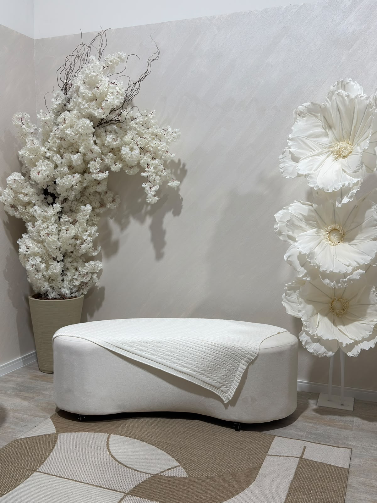 Cenário clean do Estúdio 428 em tons neutros com banco claro e flores brancas