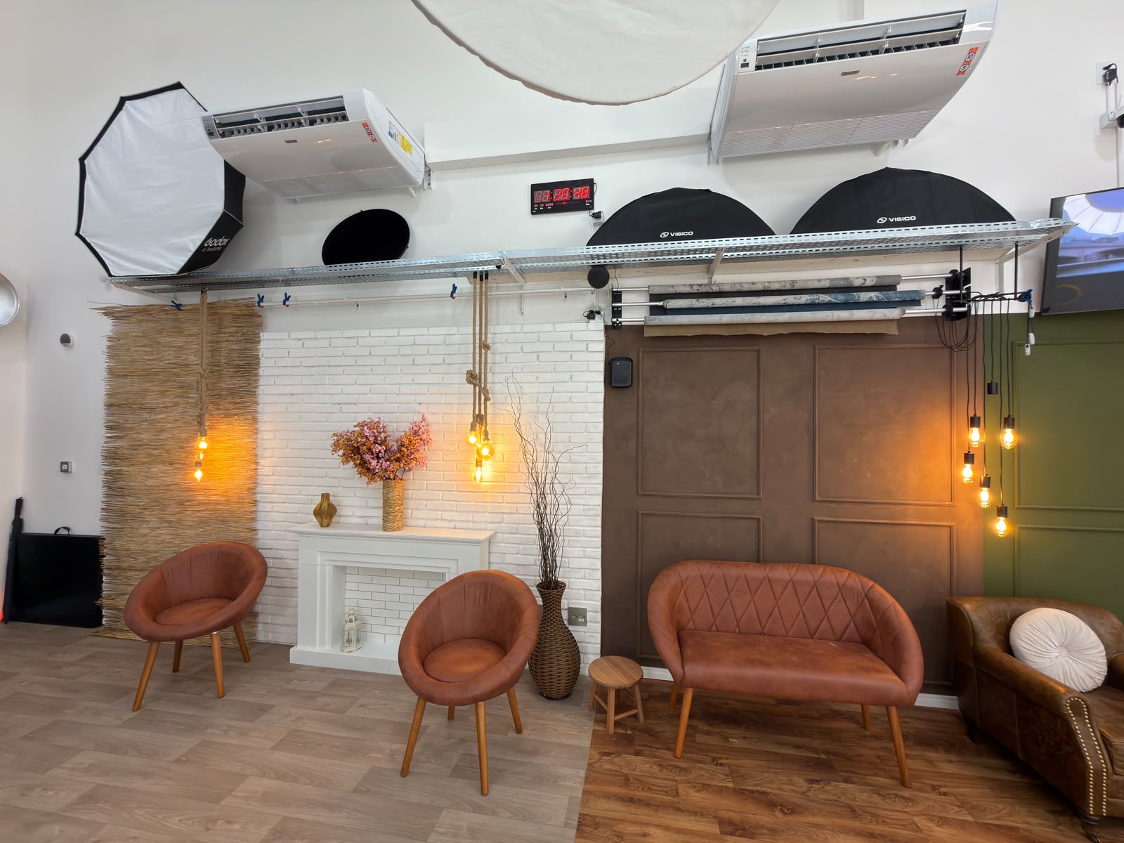 Cenários do Estúdio 428 com parede de tijolo branco, lareira decorativa, poltronas e fundos intercambiáveis